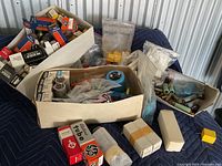 Three cardboard boxes on moving blanket containing tube boxes, loose tubes, plastic connectors and blue plastic component