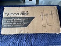 Photo of the PrimeCables branded cardboard box for a Universal Tabletop Stand for TV and AV devices.