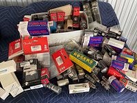 Assortment of vacuum tubes from various brands in a cardboard box