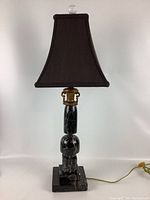 Full view of the lamp showing black fabric lampshade, gold-toned collar, and the black marble base with etched white veining.