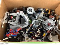 Top-down image of box filled with mixed Lego pieces including partial builds and loose bricks