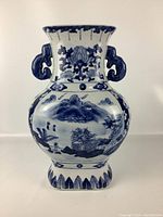 Full front view of the tall vase showing hand-painted blue landscape and floral design with double handles and flared neck.