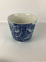 Front angle view of blue and white Staffordshire ceramic vase showing detailed rural cottage and tree landscape pattern.