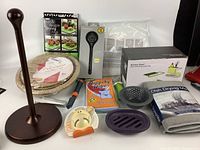 Photo of all kitchenware items laid out including paper towel holder, drying mats, digital thermometer, soap caddy, cleaning wipes, kitchen tools, and storage baskets