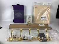 Purple pillowcase, cream fabric organizer, lemon soap box and gold plated 5-hook rack in plastic packaging arranged on white surface