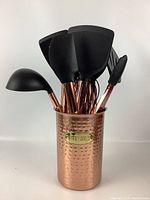 Full view of the 10 kitchen utensils with black rubber tips and copper-colored plastic handles inside the hammered copper-tone metal canister labeled 'Utensils'.