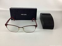 Front view of Prada glasses with carrying case and outer box