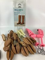 Wide shot showing all types of shoe and boot shapers including wooden shoe trees, plastic stretchers, and boot forms in pink and cream colors.