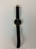 Full view of the ladies Skagen Ditte watch showing the black leather strap, gold bezel, and black dial face.
