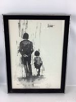 Full view of framed black and white Aldo Luongo print showing two figures walking away, the frame is black with visible minor wear.