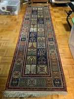 Full view of the entire vintage hand knotted runner rug showing its rectangular shape, fringe, and border pattern.