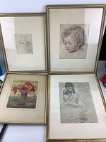Four framed prints displayed together showing variety of sketches and floral print.