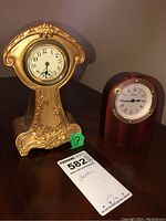 Front view of both clocks showing metal decorative clock on left and Birks wood clock on right