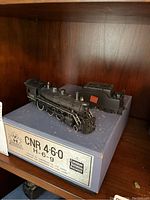 Locomotive and caboose displayed on original blue box inside wooden cabinet