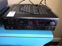 Front view of the Denon DRA-295 Stereo Receiver showing the power cord on top and logo on the left.