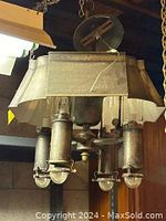 Full view of metal light fixture with four glass shades hanging from a chain, showing the top metal canopy and cylindrical holders.