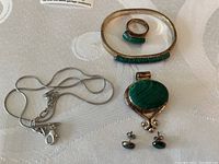 Overview of entire Mexican silver jewelry set with bracelet, ring, earrings, pendant and chain visible on textured fabric.