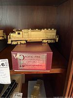 Side view of the unpainted brass Pacific Pike GP-40 model train shown atop its original box with label
