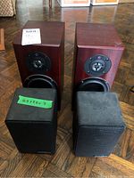 All four speakers on floor showing two cherry veneer Totem Dreamcatcher and two black AudioSource LS-ONE units