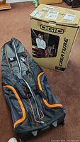 OGIO Creature golf travel cover in black with orange detailing beside its original cardboard box