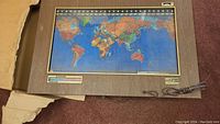 Full view of electric world map in wood frame with power cord.