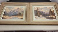 Two framed prints side by side showing mountain and river landscapes.