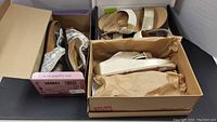 Three pairs of women's sandals in open boxes: Papillio sparkly silver sandals, Bionic beige and gold sandals, and Fitflop gold sparkle sandals with bow detail.