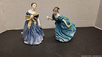 Front view showing two Royal Doulton figurines, one in blue dress with yellow shawl and one in blue dress holding a rose