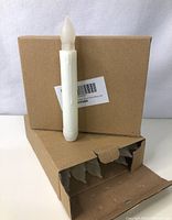 Battery operated LED candle shown standing against closed brown box, showing the candle and box packaging.