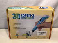 Photo of the original packaging of the 3D Pen 3DPEN-2 with printed product specifications and images of 3D printed models (Eiffel Tower, butterfly)