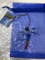 Crystal Art dragonfly suncatcher with faceted clear crystal wings and colorful bead body, shown against a white background with blue organza pouch and seller tag.