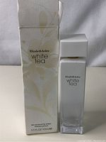 White Tea perfume bottle next to its box showing product name and volume.