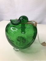 Front view of green crackled glass fruit fly trap shaped like an apple with a duck head stopper and attached string.