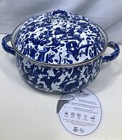 Full view of the Dutch oven with the lid on showing blue and white speckled enamel design and two side handles.