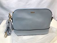 Image showing light blue Lovevook purse resting on white cloth background, with detachable strap attached.