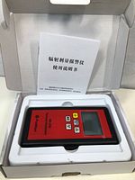 Top-down view of the radiation detector in its packaging showing the manual and device.