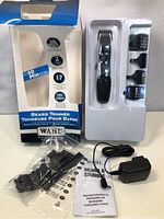 Photo showing Wahl beard trimmer, three attachment combs, charger base with power adapter, instruction manual, and original box with torn top flap