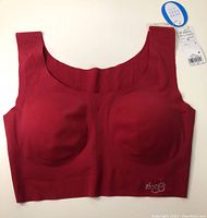 Top down view of a new women's padded sports bra in medium size. Solid red color and seamless design visible. Original tags attached.