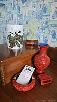 Overall view of lot including red cinnabar vase, ashtray, desk piece, porcelain brush pot, and jade carving on stand