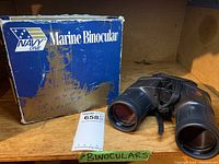 Navy One Marine Binoculars placed next to original blue box with 'Marine Binocular' text, showing wear on the box.