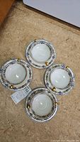 Four Limoges bowls placed rim to rim showing their inner floral pattern and gold handles.