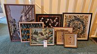Eight framed needlepoint wall art pieces displayed together, showing variety of designs, sizes, and frame styles.