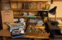 Wide view of entire lot showing vintage telephone, lamp, stapler, hole punch, magnifying glasses, rulers, and boxes with pens and pencils.
