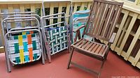 Wooden folding chair and five metal-framed lawn chairs of various colors and wear.