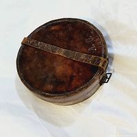 Top view showing circular shape, leather surface and attached strap.