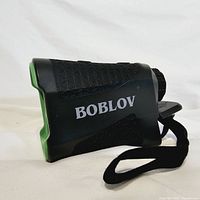 Side view of the BOBLOV rangefinder showing black body with green accents and large BOBLOV logo.
