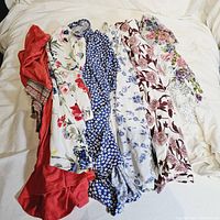 Five ladies short sleeve tops laid out, 4 floral pattern tops and 1 solid coral red top visible