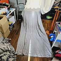 Single Ikea Lunda curtain panel draped from a height showing full length and texture of dark gray fabric with wrinkle detail.