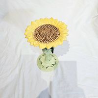 Photo showing front view of ceramic sunflower pedestal stand with yellow flower top and green stem base