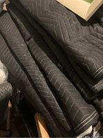 Stack of black and gray moving pads showing quilting and fabric texture.
